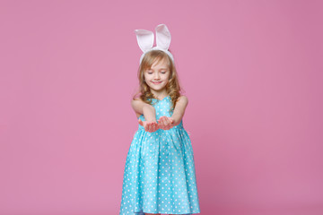 Obraz na płótnie Canvas Cute little blonde girl in the shape of an Easter Bunny and a blue dress with a pea pattern. Concept of the celebration, advertising and fashion. happy Easter. Selective focus.