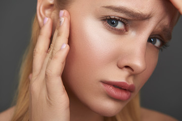 Worried woman frowning and checking her skin on the face