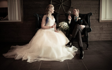 bride and groom sitting inside with a glass og champagne