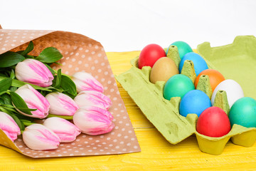 Obraz na płótnie Canvas painted eggs in egg tray. Happy easter. Spring holiday. Holiday celebration, preparation. Egg hunt. Tulip flower bouquet. Healthy and happy holiday. Look over there