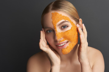 Calm woman touching her temples while having orange mask on the face
