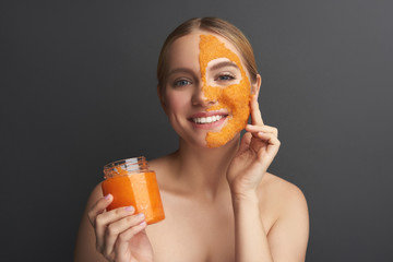 Portrait of positive lady with orange peel mask on her facial skin
