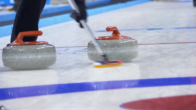 Curling player throw and delivering a stone on a curling rink, sliding over ice