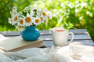 cup of tea, book and summer flowers in the garden. Reading a book or education. Summer concept