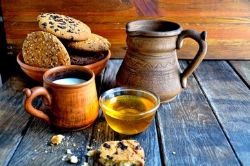 Fototapeta na wymiar Oatmeal cookies in a ceramic rustic plate, milk in a ceramic mug, napkin, honey on a rustic wooden table.
