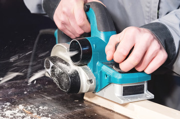 The hands of a carpenter working woodworking power tools. Close up of the work of the electric...
