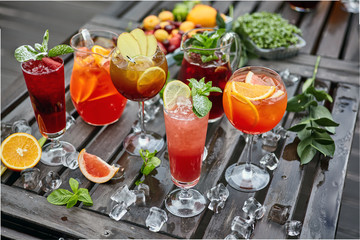 Cocktails of different colors on a wooden table covered with ice