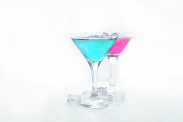 martini glasses with colored drinks and ice cubes.