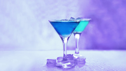martini glasses with colored drinks and ice cubes.