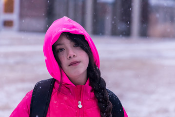 Young Asian Girl with pink jacket standing in front of building