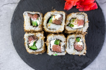 Sushi rolls with salmon, vegetables, ginger on black background. Japanese food, sea food concept