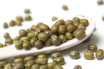 Closeup of mungo beans in a white spoon  on white background