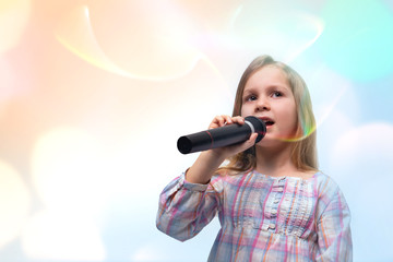 Little girl with a microphone in her hands sings a song, isolated on white with copy space