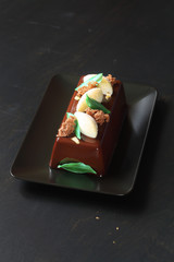 Contemporary Chocolate Mousse Cake with Lemon Curd Center covered with chocolate mirror glaze, on dark background.