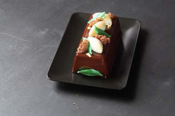 Contemporary Chocolate Mousse Cake with Lemon Curd Center covered with chocolate mirror glaze, on dark background.