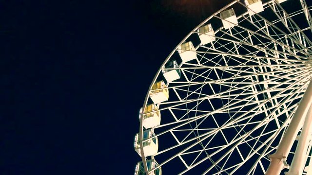 Ferris wheel. High luminous carousel on a dark background. Evening video. Blue background