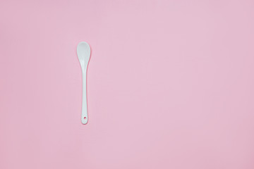 Ceramic white spoon on a pink background copy space