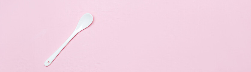 Ceramic white spoon on a pink background copy space