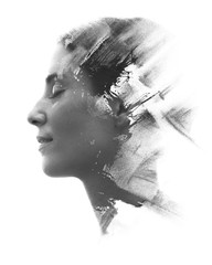 Paintography. Double exposure portrait of a young woman’s profile combined with handmade painting with a texture of brushstrokes disappearing into her face. Black and white