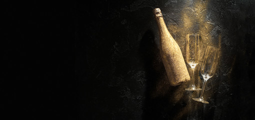 Fototapeta Photo of golden champagne bottle, two wine glasses on black stone background obraz