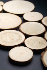 Pine tree cross-sections with annual rings on plane black surface. Lumber piece close-up shot.