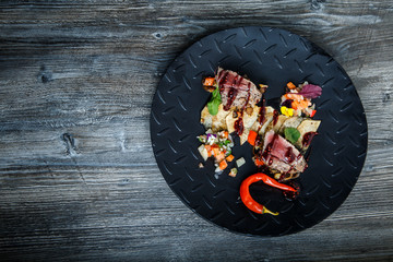 top view two pieces of medium raw grilled meat with red pepper and sauce