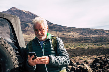 Caucasian old man use modern technology cellular phone at the mountain during trip vacation with...
