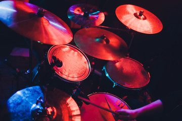 Drummer playing drum set at concert on stage. Music show. Bright scene lighting in club,drum sticks...