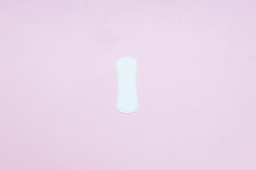 White ladies panty liner on bright pink paper background. Top view, close up copy space, flat lay