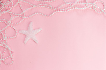 On a pink background is a white starfish, around a necklace of pearls.