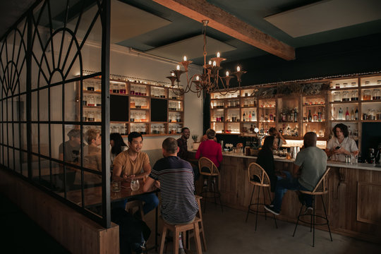 Diverse people enjoying drinks at a bar in the evening