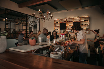 Laughing couple talking with a bartender in a pub