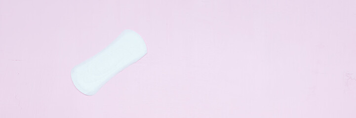 White ladies panty liner on bright pink paper background. Top view, close up copy space, flat lay