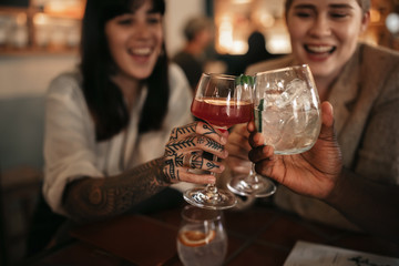 Smiling friends toasting together with drinks in a bar