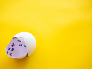A broken egg with a countdown inside it and feather on a pastel blue background. Concept of freedom