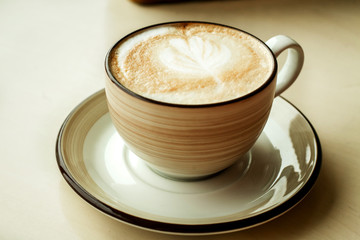 fresh cappuccino in a Cup on the table, a Cup of hot coffee, coffee with a foam pattern