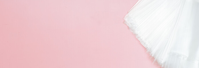 Few cellophane bags packs. White bags package template in corner pink background copy space flatlay long banner