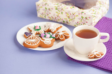 Homemade gingerbread, spring provence. Mother's Day. Sweet flowers, butterflies, a Sweet flowers, butterflies, a bicycle, and tea on the table. Lilac background.