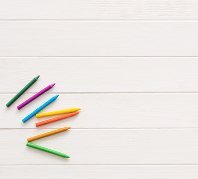 Colorful wax crayons for drawing on the white wooden table. Top view and copyspace. space for caption, empty space for text