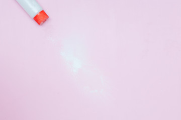 Bottle of Talcum baby powder on pink background. Powder spilled from white container, top view flatlay