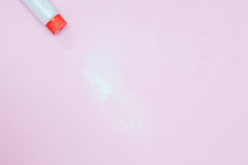 Bottle of Talcum baby powder on pink background. Powder spilled from white container, top view...
