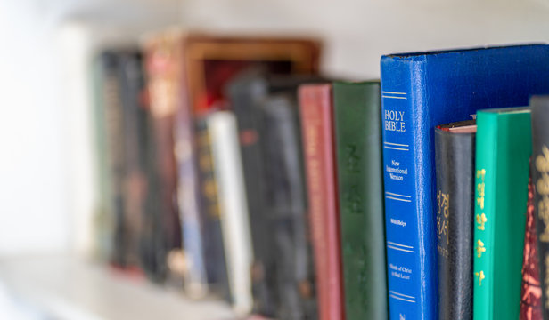 CHIANG MAI, THAILNAD - 24 JANUARY 2019 :  Numerous Holy Bibles sit in a row on wooden shelf. Bookshelf with used prayer books inside..