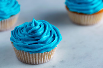 Cupcakes with blue icing on a white marble worktop