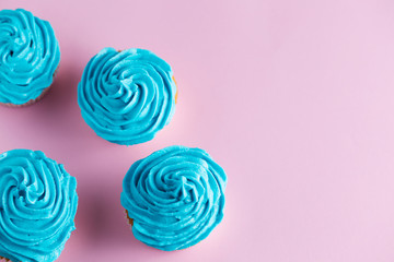 Cupcakes with blue icing on a pink worktop