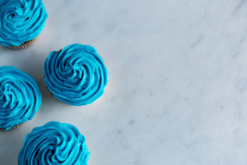 Fototapeta na wymiar Cupcakes with blue icing on a white marble worktop