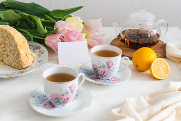 Tea party with homemade cake, lemon, teapot and tulips on the background. Copy space