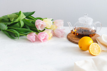 Obraz na płótnie Canvas teapot with black tea, lemon and flowers on white table. Copy space. Spring tea party