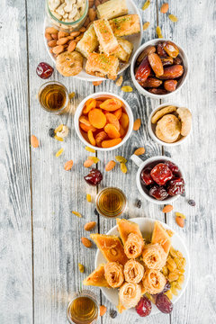 Set various Middle Eastern Arabian sweets - Turkish baklava, knafeh (kunaf), nuts, dried fruits and seeds. White wooden background, top view copy space