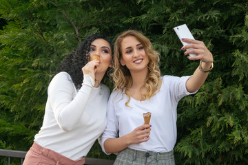 Two girls are taking selfies and eating ice cream