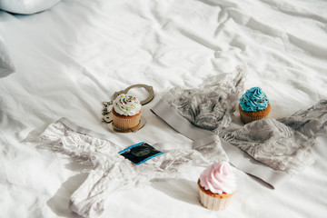 Obraz na płótnie Canvas tasty cupcakes near lace underwear, handcuffs and condom